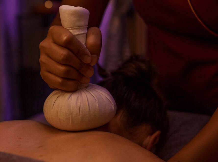 Warmer Kräuterstempel bei einer Thai Kräuterstempelmassage am Rücken