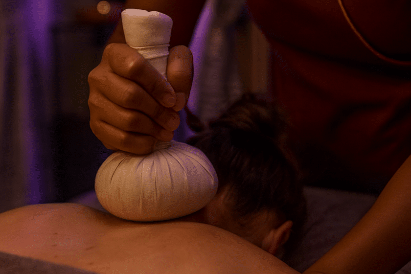 Thailändische Masseurin in lila Uniform führt eine entspannende Massage im Spa-Raum von Milanee Thaimassage in Nürnberg durch.