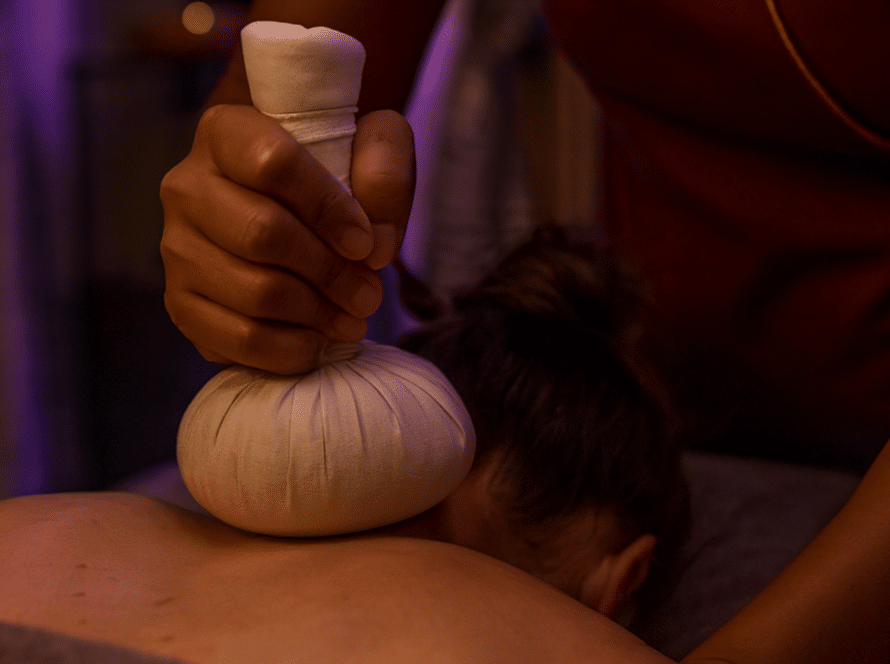 Thailändische Masseurin in lila Uniform führt eine entspannende Massage im Spa-Raum von Milanee Thaimassage in Nürnberg durch.